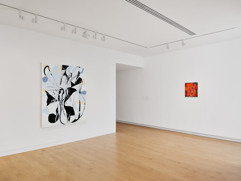 Abstract paintings on a museum wall. One is larger and white and black, the other is smaller and red.