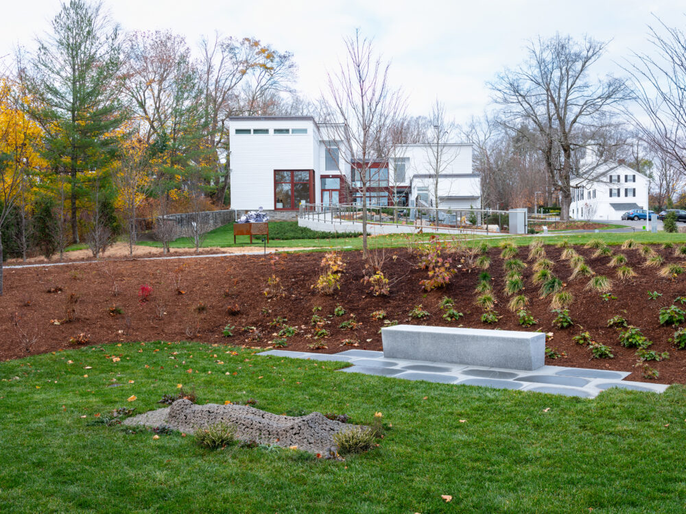 An exterior view of a garden displaying a shroud sculpture in the foreground.