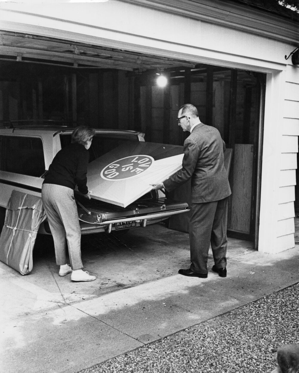 Larry Aldrich loading Love Is God by Robert Indiana into the back of a station wagon for transport.