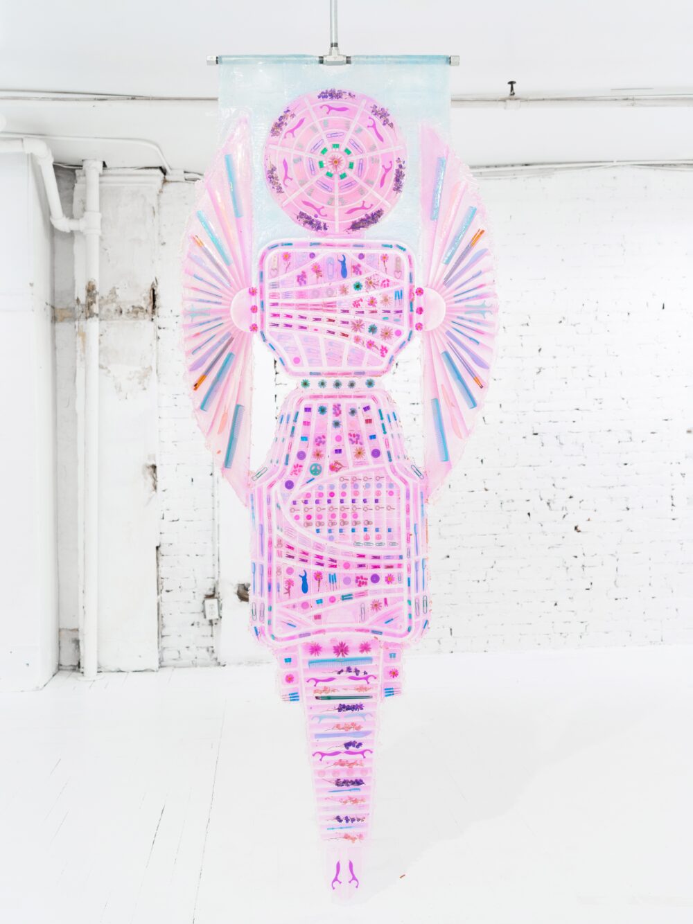 A pink banner made of platinum silicone, pigment, flowers, and miscellaneous objects.