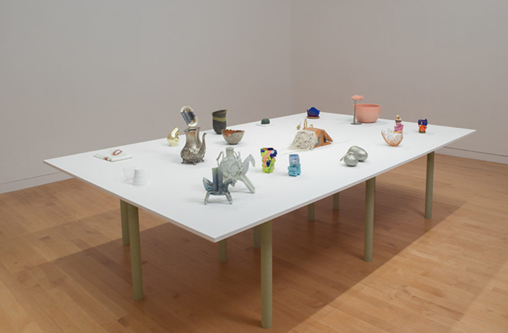 Small sculptural objects sit on a white table