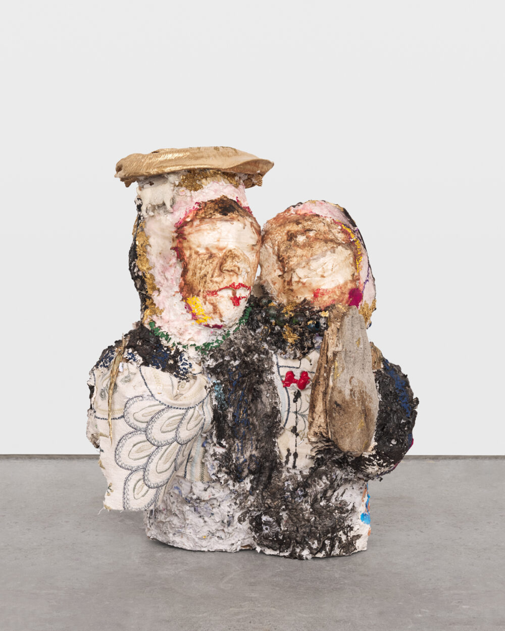 White, black, and gold sculptural artwork of two abstract figures.