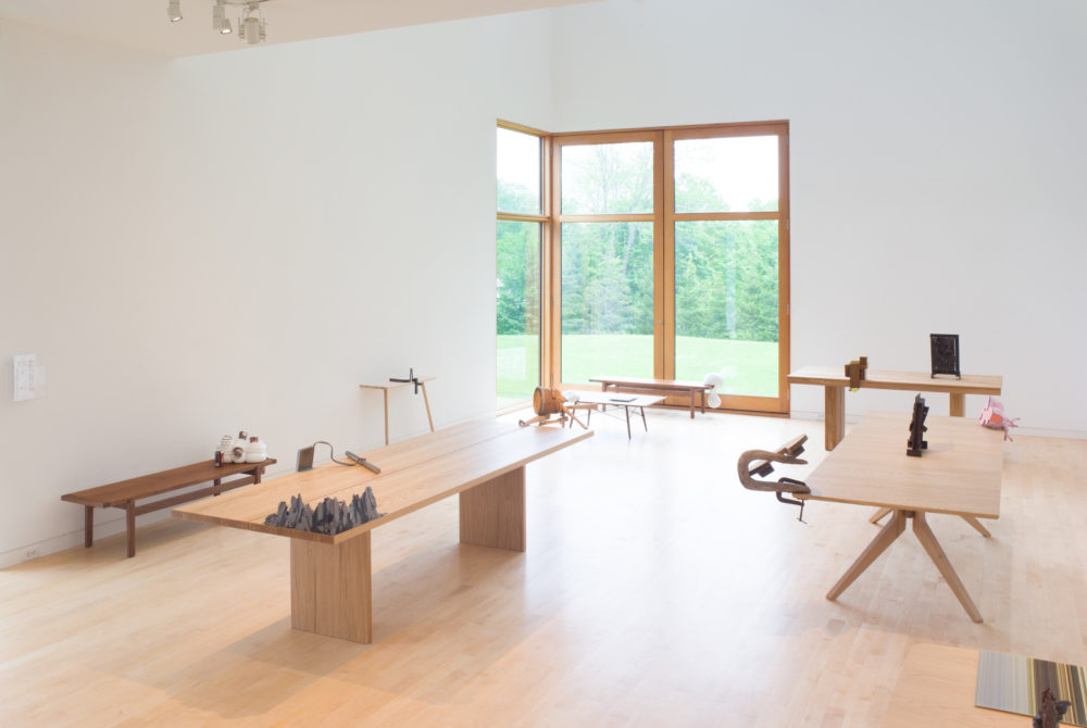 Small objects sit on tables in gallery