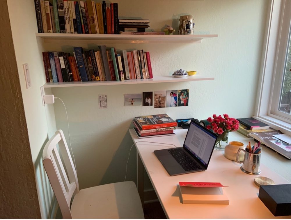 Laptop sits open on a desk with a bookshelf in the background