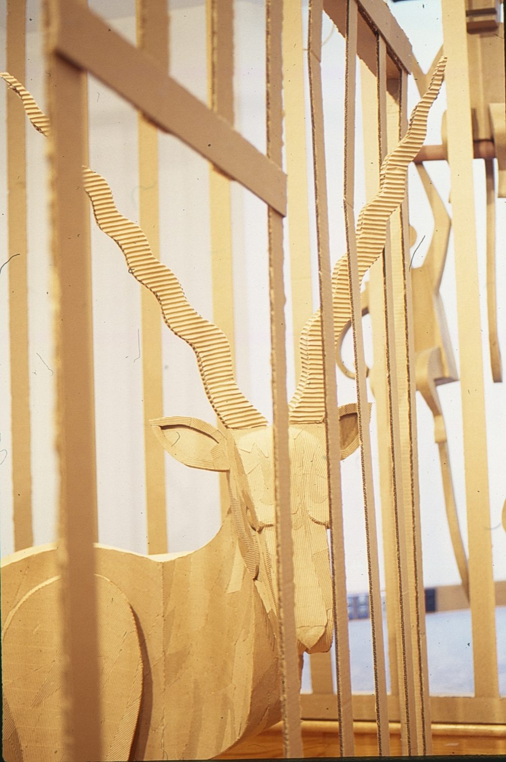 A cardboard antelope behind a cardboard cage