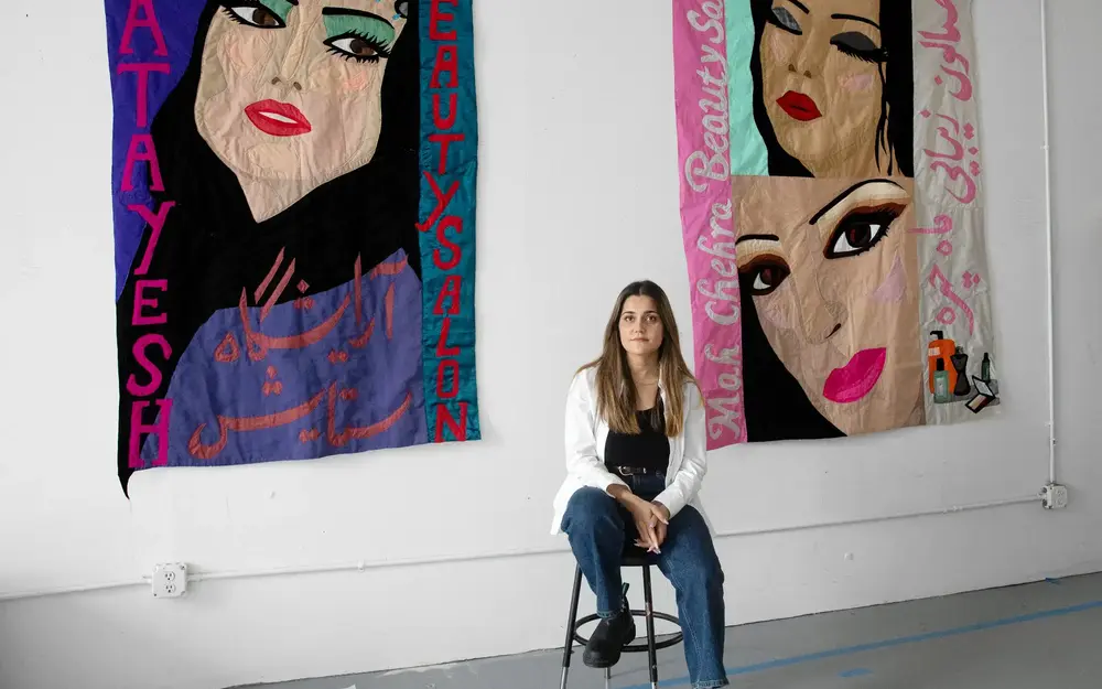 Hangama Amiri with two of her works, from left, “Setayesh, Beauty Salon” and “Mah Chehra Beauty Parlor,” both from 2022.