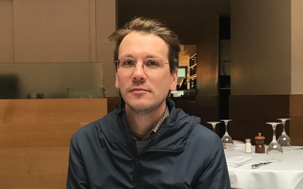 Headshot of a man in a restaurant-setting looking directly at the camera.