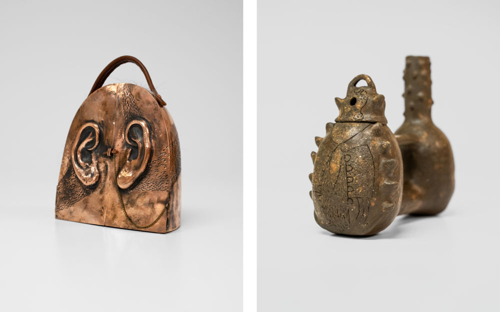 Two brown handheld sculptures. The one on the left has ears, french doors, and a handle. The one on the right is a traditional whistling jar.