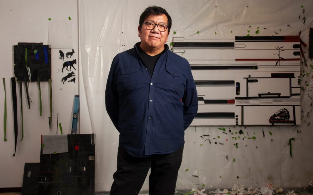 Duane Slick standing in his studio with an in-progress painting behind him.