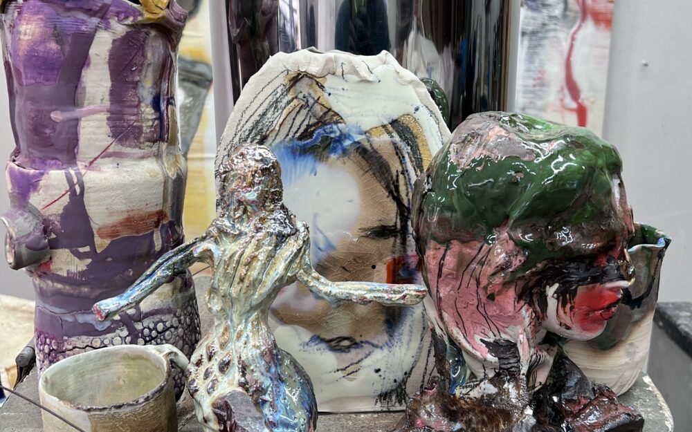 Various glazed ceramics with figurtive and abstract elements on top of a kiln.