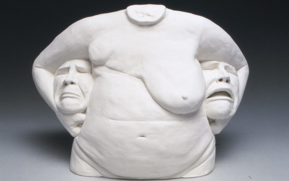 ceramic torso with breasts with a head tucked underneath each arm