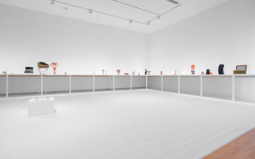 Small sculptural objects on shelf in white room