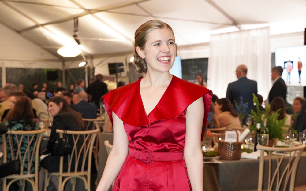 Young woman in a red Larry Aldrich dress from the 1950s, smiling at a Gala.