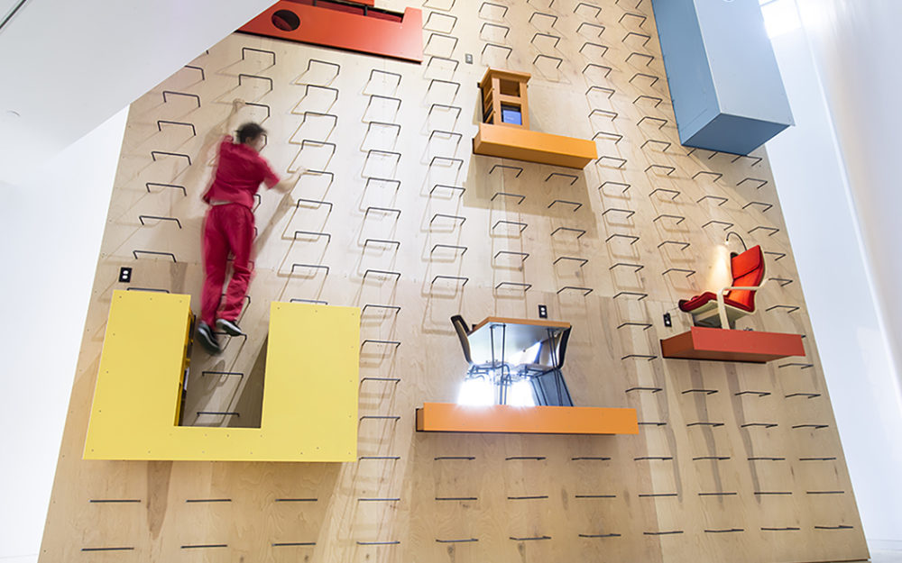 Person scales a large wall installation