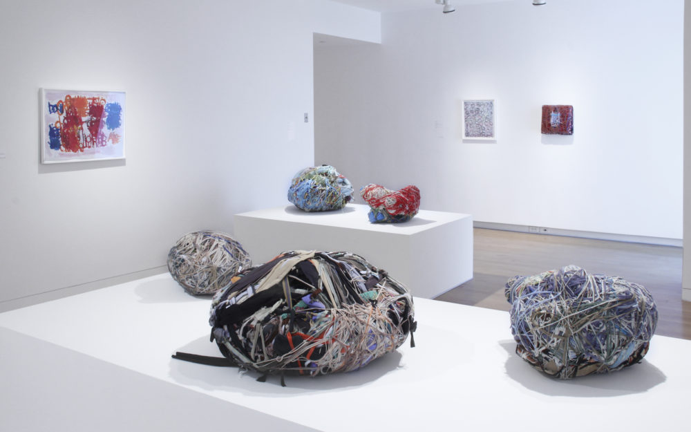 Sculptural objects on white platforms in gallery