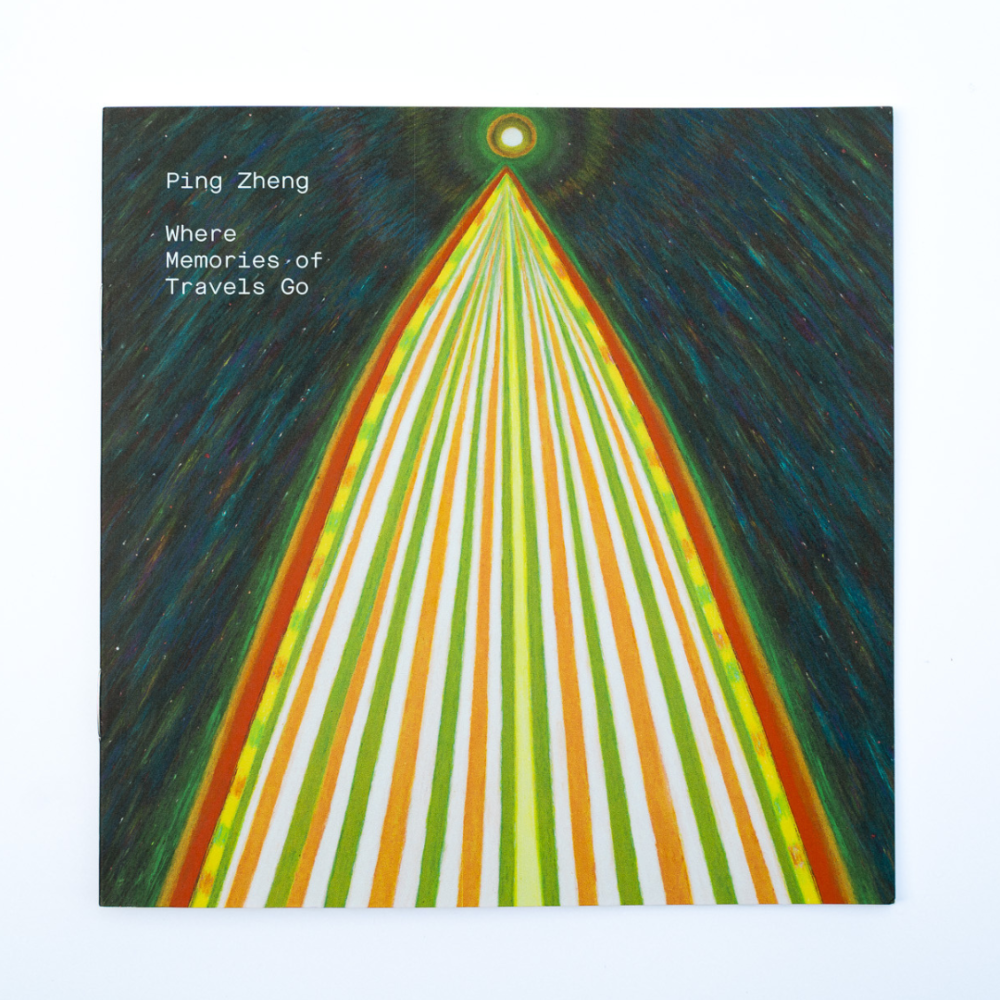 A photo of a square 'zine booklet with a striped triangular form pointing towards a glowing orb in space.