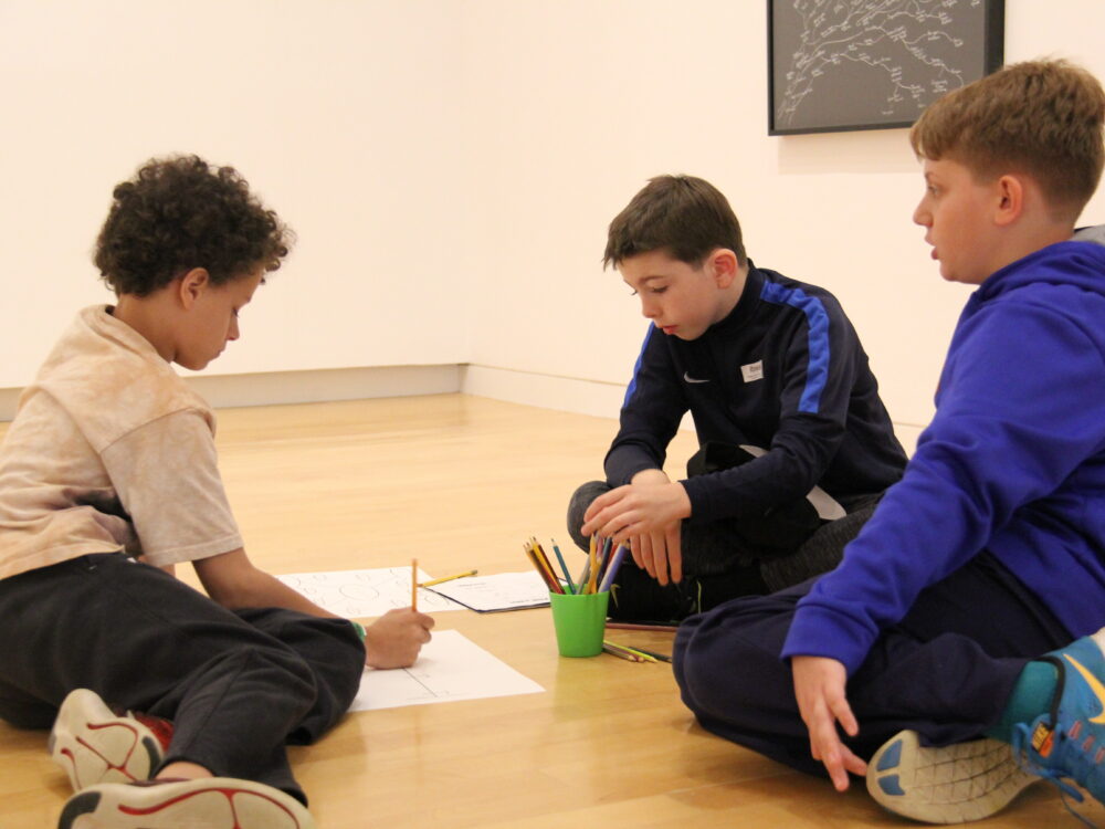 Three children work on art projects