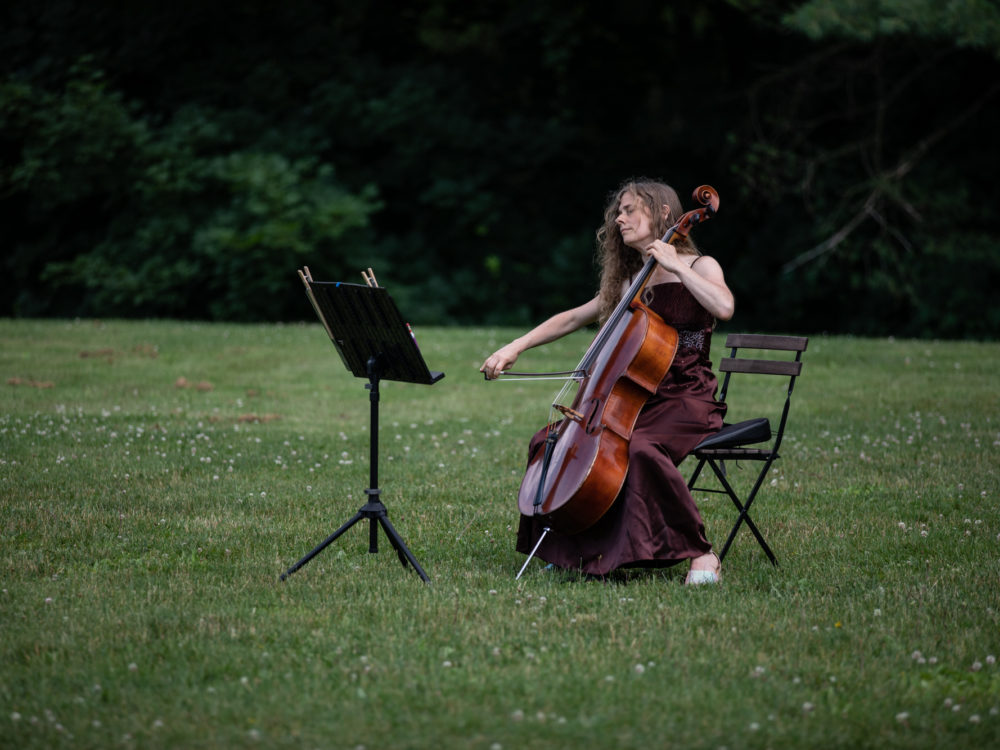 A musician performing seated in a chair in a field
