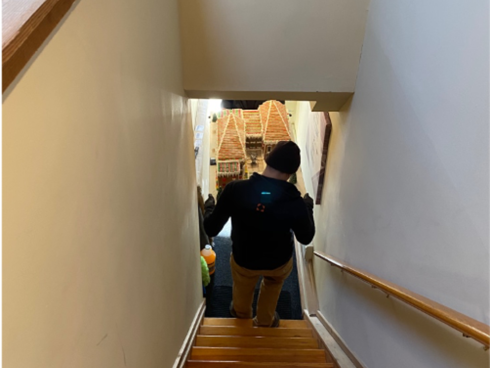 Two art handlers move Caitlin's gingerbread house down the stairs