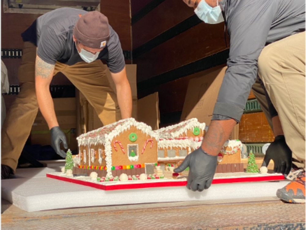 Two art handlers configure Caitlin's gingerbread house in a moving truck