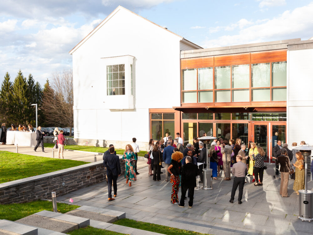 The Museum's facade with people socializing on the front terrace.