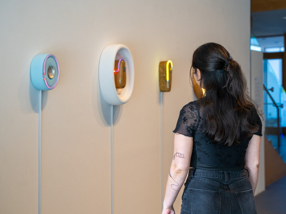 a woman looking at neon sculptures on a wall