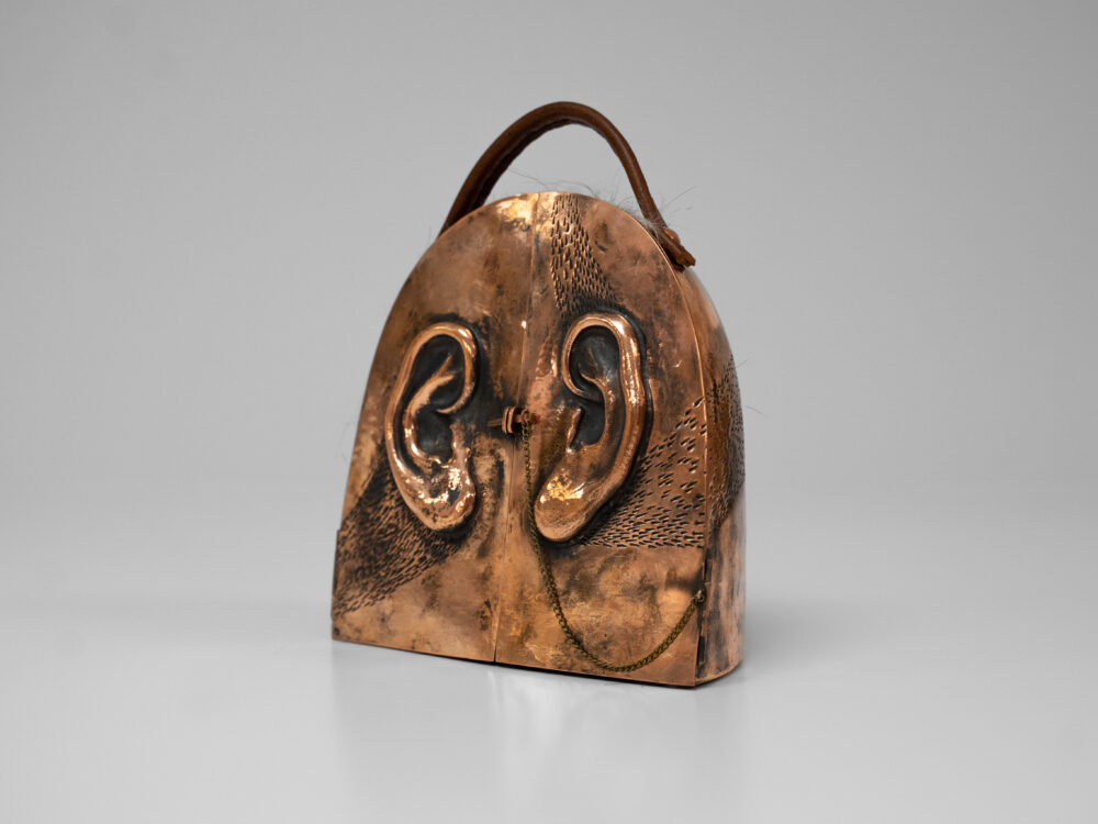 Copper box with ears carved on the front two doors with a handle on top.