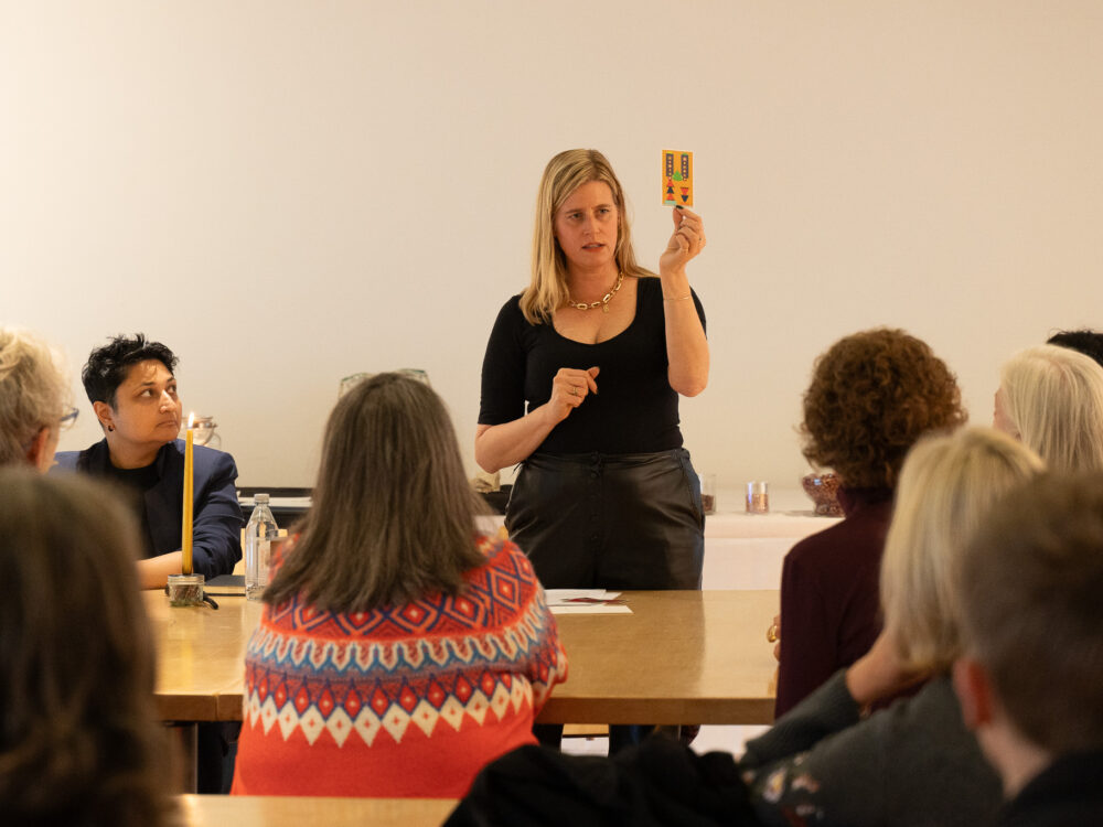 A woman holding up a card to a class learning about witchcraft.