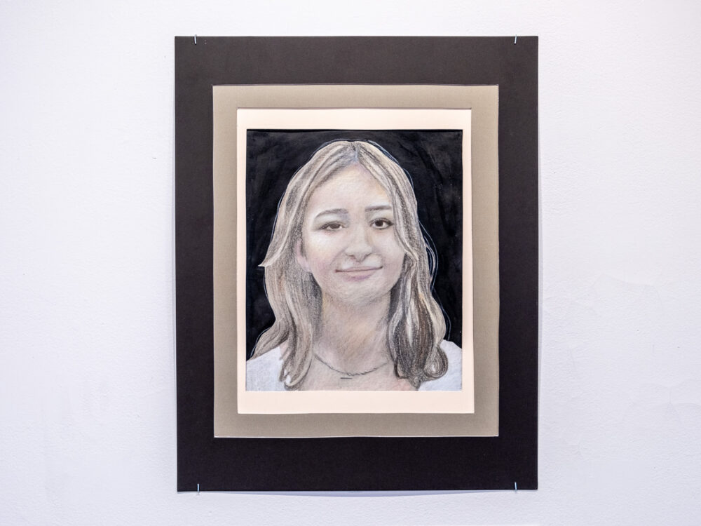 A colored pencil drawing of a young woman on grey toned paper.