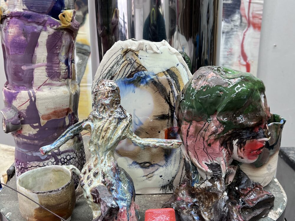 Various glazed ceramics with figurtive and abstract elements on top of a kiln.