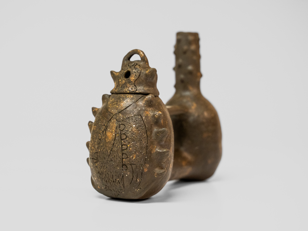 A brown had carved ceramic traditional whistling jar by artist Koyolzintli.