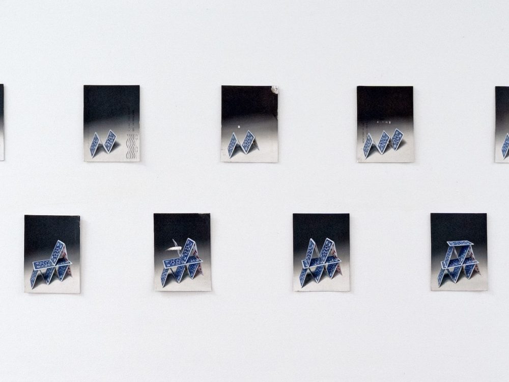 Small paintings of a house of cards slowly being built.