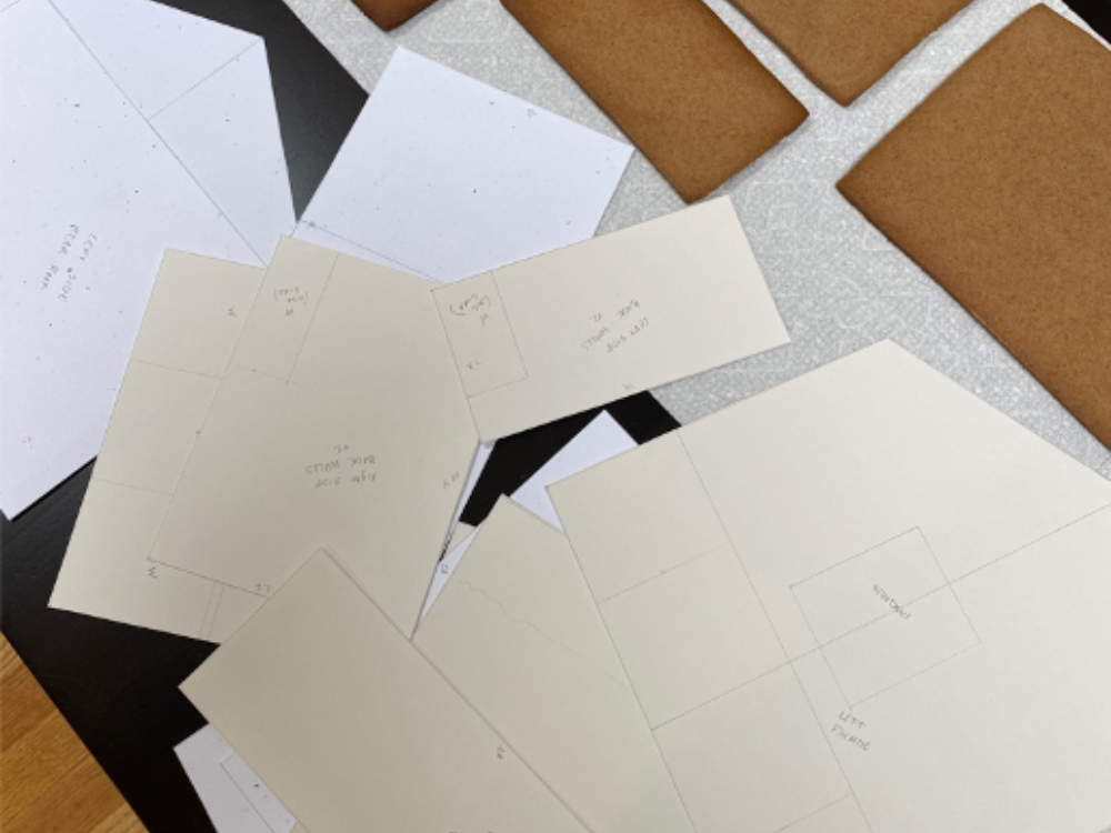 Blueprints of The Aldrich Museum with gingerbread pieces in the background