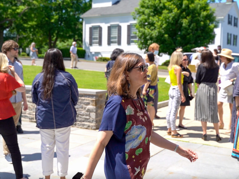 Woman walking through a crowd blowing a police whistle