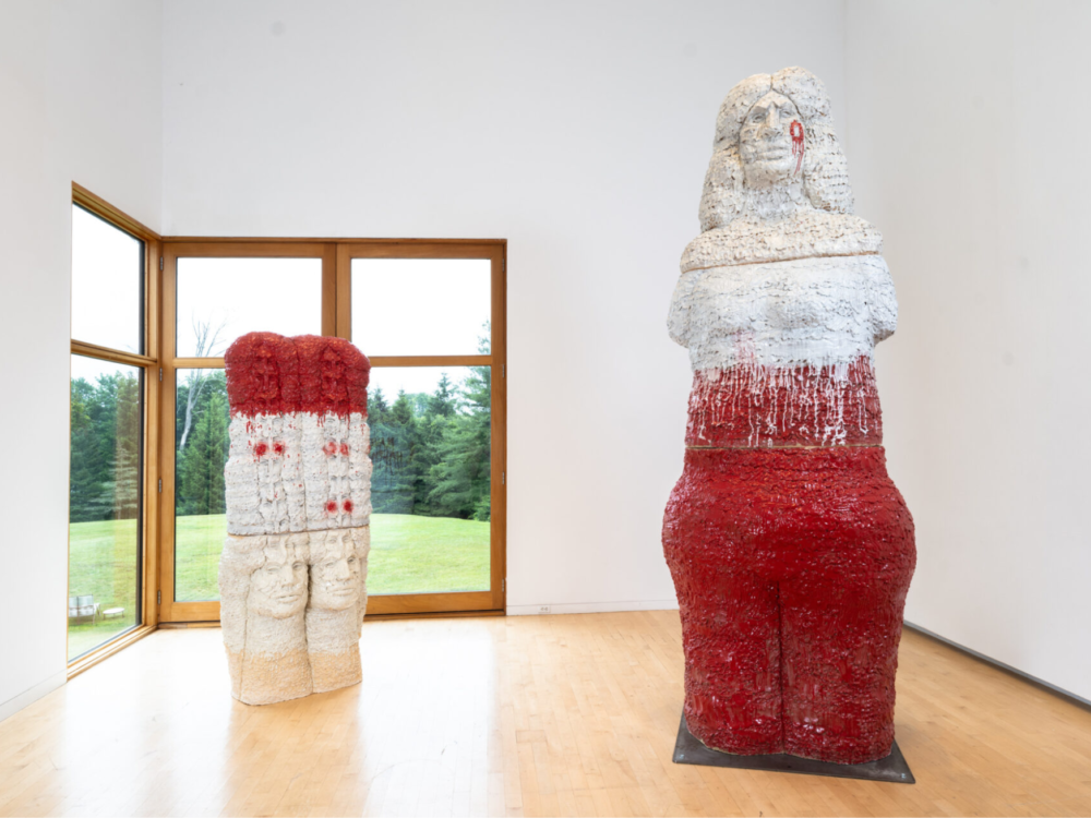 Two large-scale figurative ceramic sculptures in a gallery.