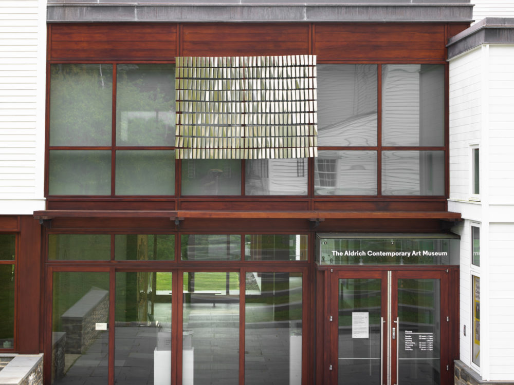 Silver rectangular kinetic sculpture installed over the entrance to The Aldrich Museum.