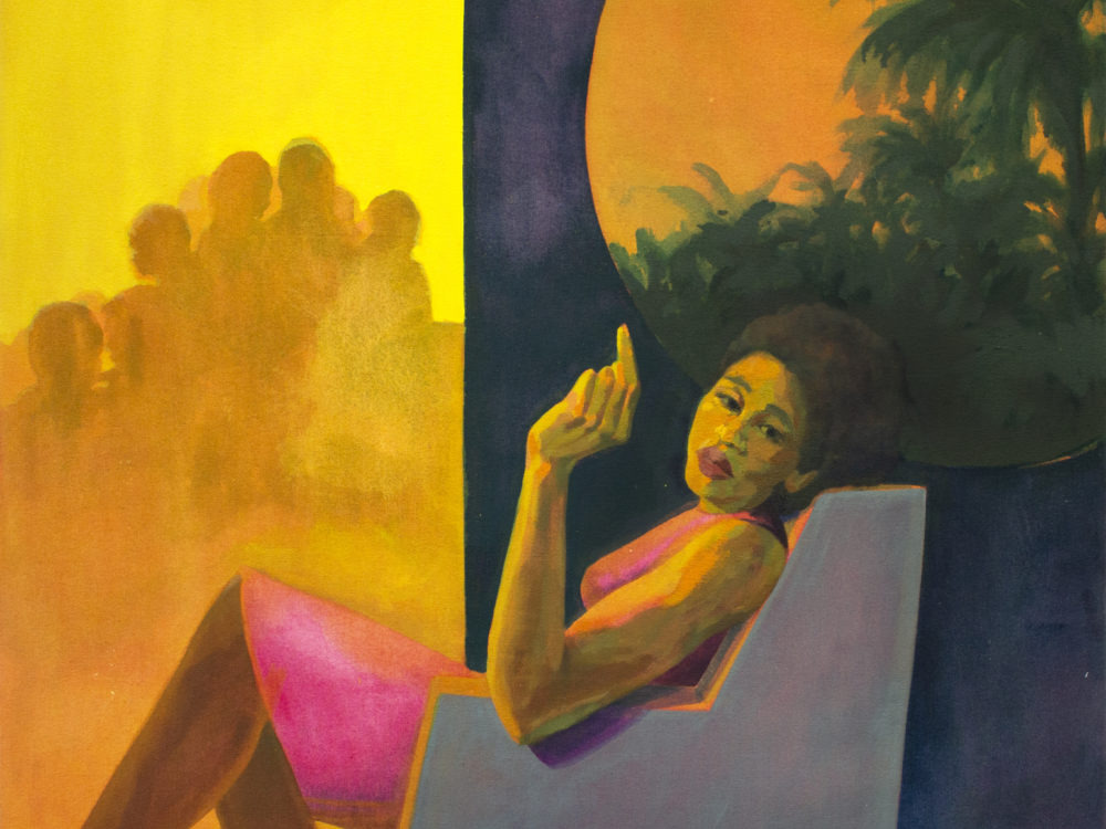 Woman seated in a gray chair looking over her shoulder holding up hr left hand pointing a finger with palm trees in the background