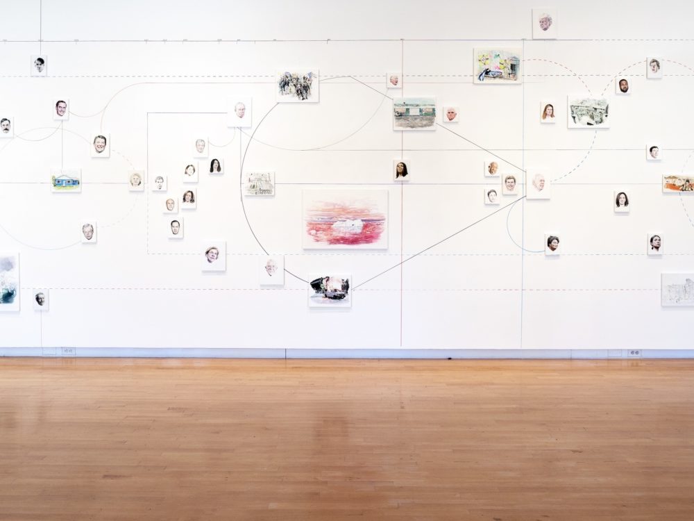Wall installation featuring many small paintings and interconnected lines.