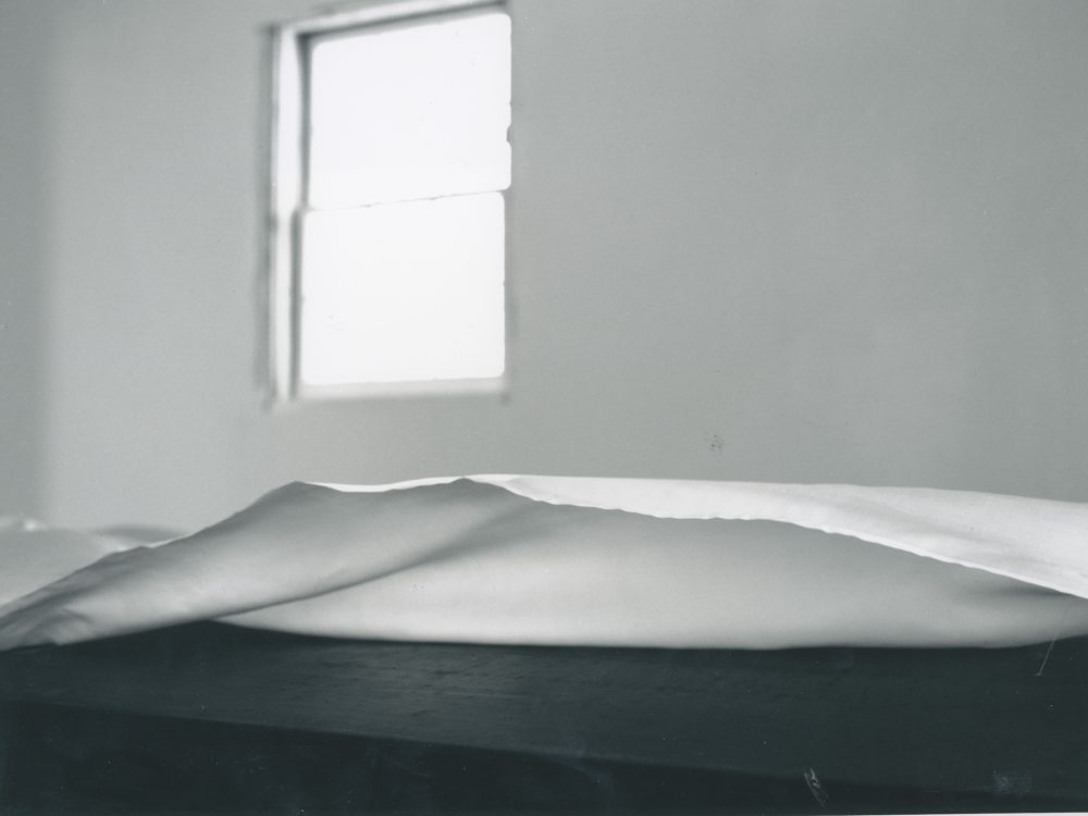 This is a detailed photograph of the white cloth which is draped over the wooden table in Ann Hamilton's exhibition