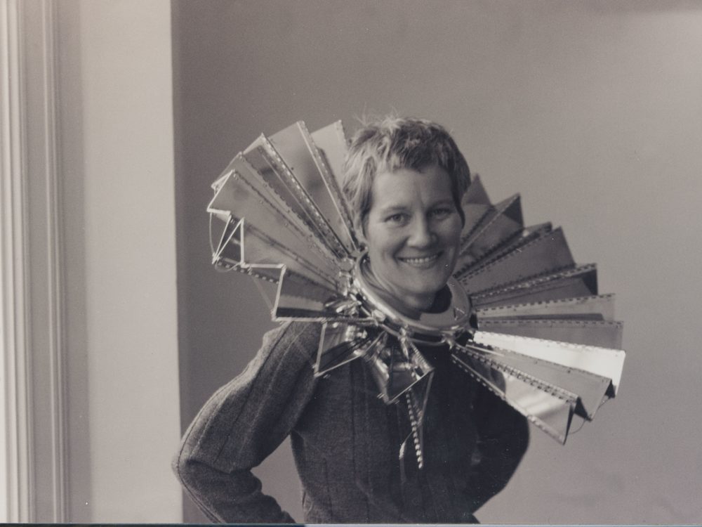 This is a photo of the artist Ann Hamilton with one of her metallic sculptures around her neck. She received the Larry Aldrich Foundation Award in 1998