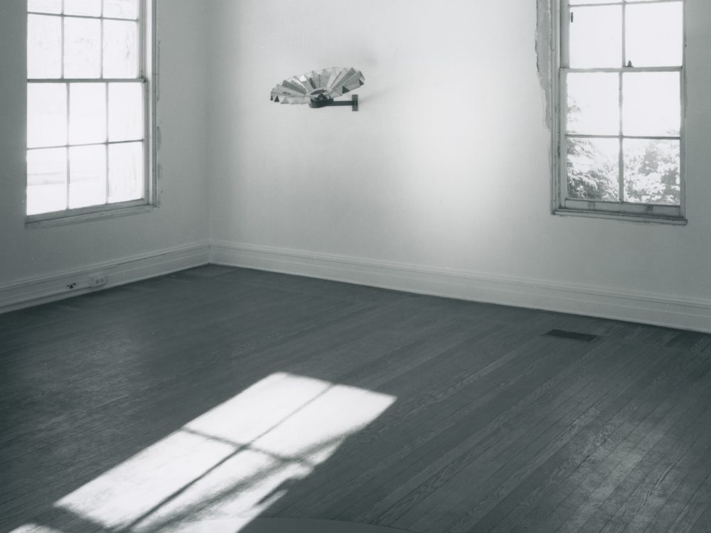 This is a photograph from Ann Hamilton's exhibition whitecloth, here you can see a metallic sculpture mounted on the wall between two windows