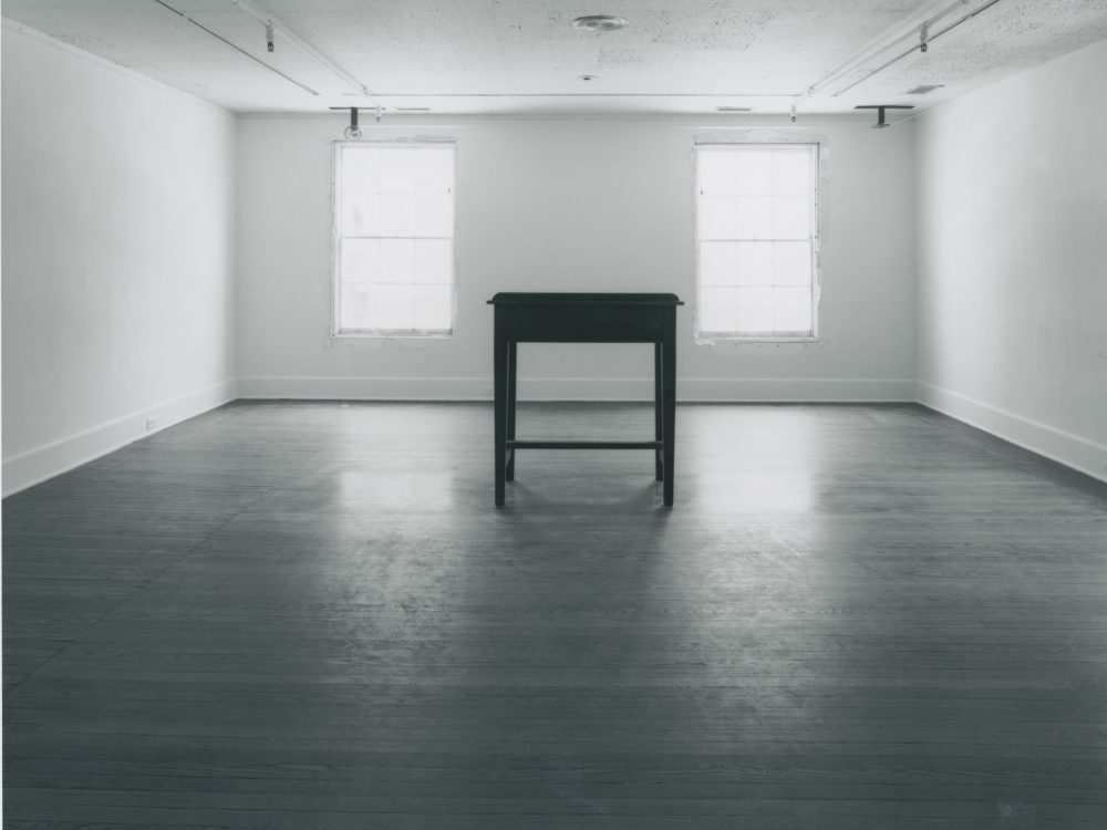 a photograph of the large gallery space with a large wooden table in the center