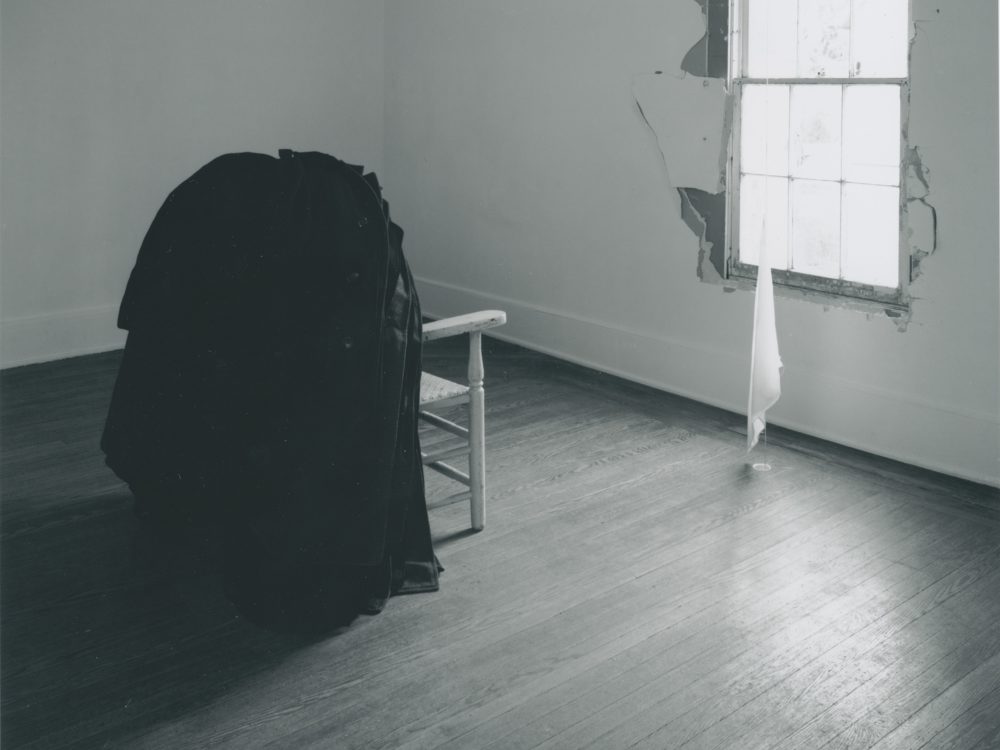 This is a photograph from Ann Hamilton's exhibition whitecloth where you can see a chair looking out the window with a small suspended cloth