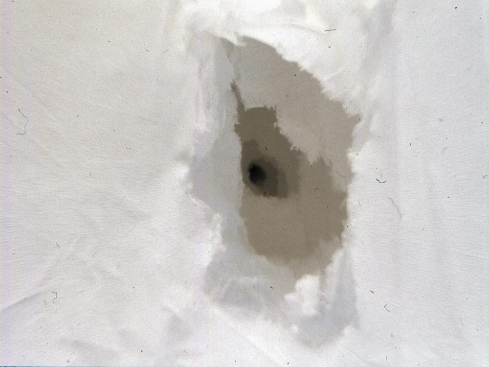 This detail looks like a hole buried beneath a series of torn papers